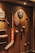 A variety of sports memorabilia displayed on a wooden wall, including a hockey stick, cricket bat, golf clubs, plaques, and balls. The lighting casts warm tones and highlights the vintage and rustic feel of the items.