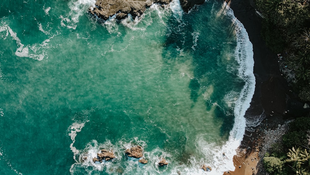 an aerial view of the ocean with waves crashing on the rocks