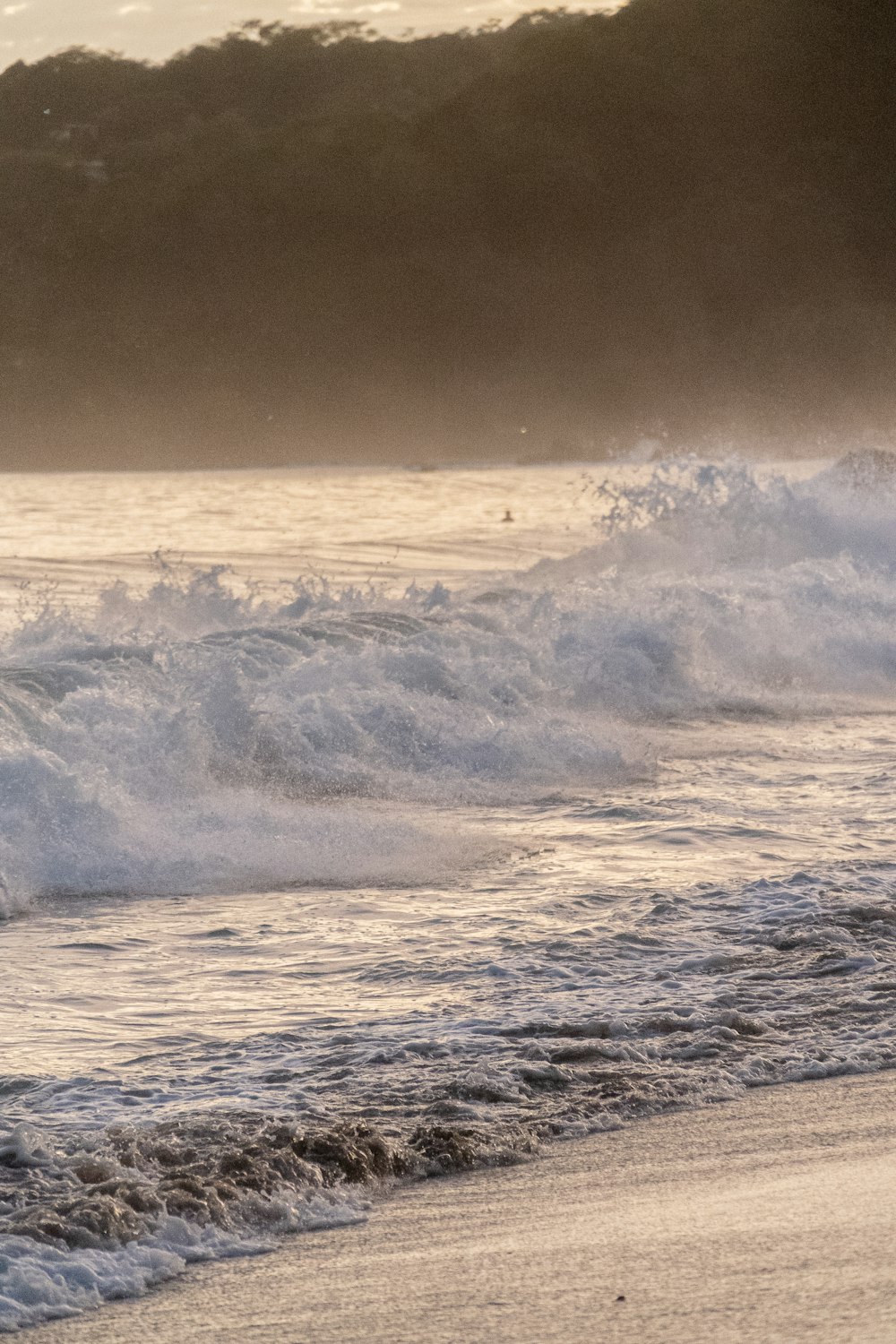 Un uomo che cavalca una tavola da surf in cima a una spiaggia coperta di onde