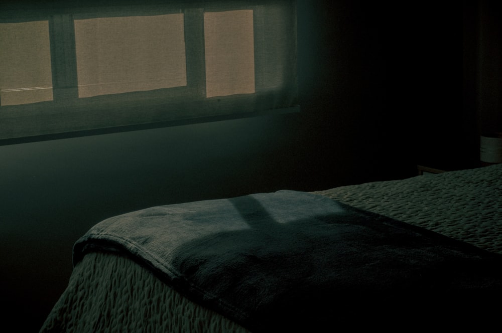 a dark room with a bed and a window