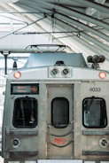 A front view of an RTD train at a station, displaying its metallic surface with visible headlights and a digital sign indicating destination 'Union Station'. The scene includes the overhead wires and part of the station structure.