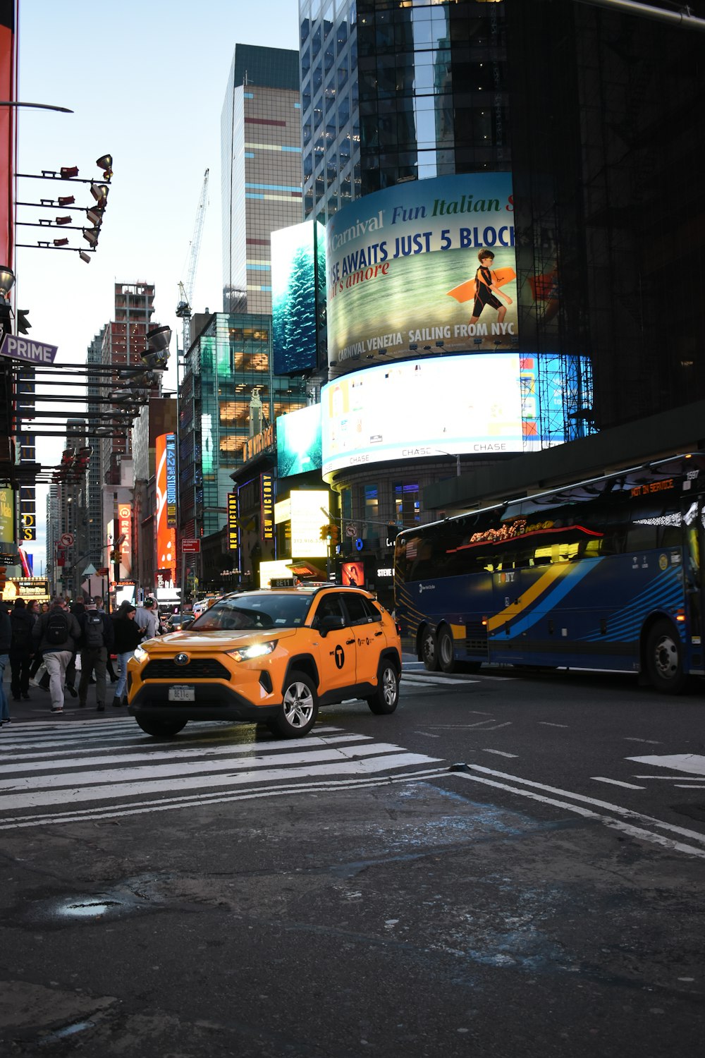 a yellow taxi cab driving down a street next to tall buildings