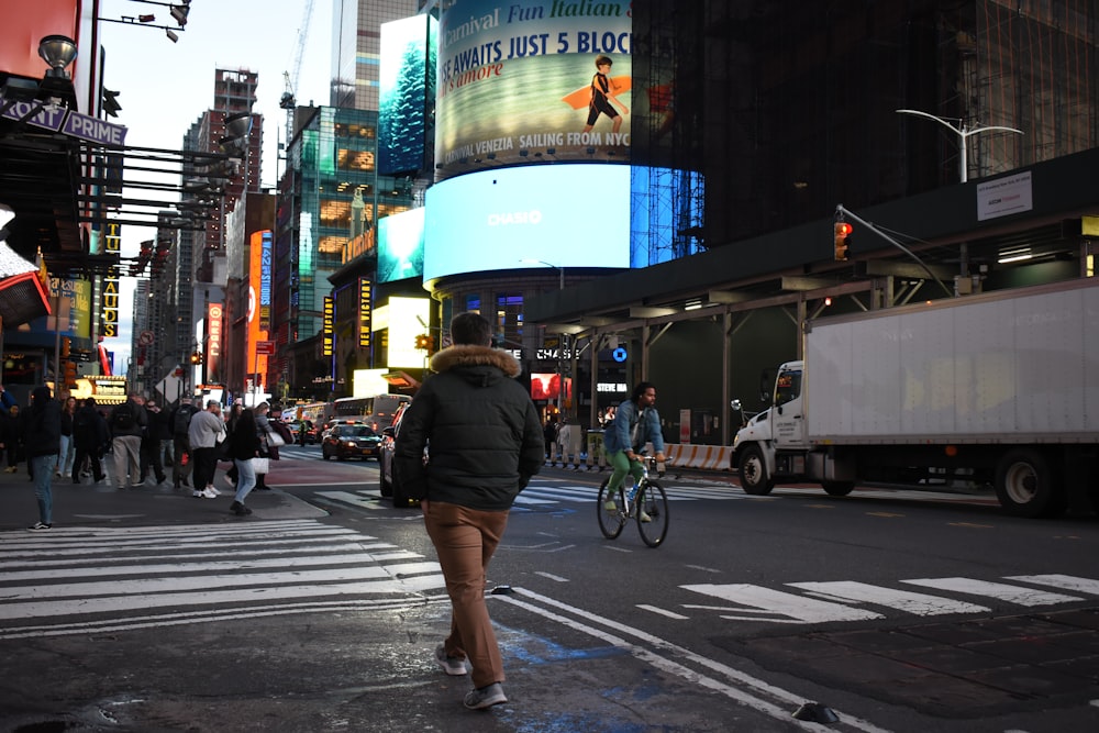 a man walking across a street next to tall buildings