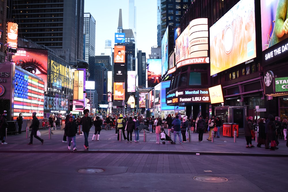 a crowd of people walking down a street next to tall buildings