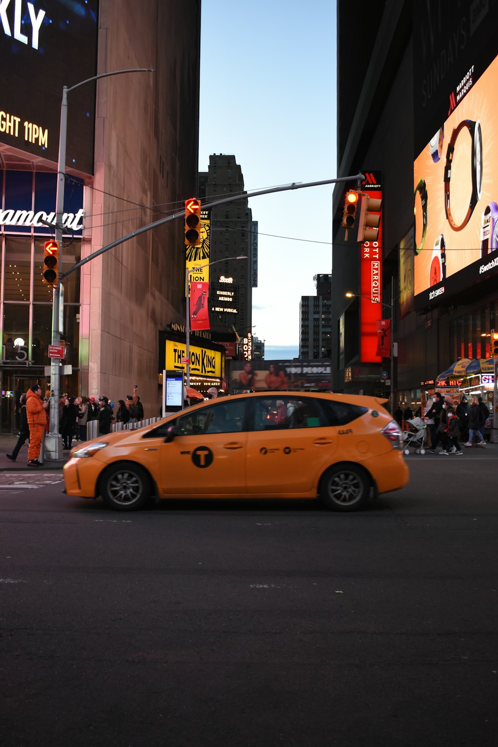 a yellow taxi driving down a street next to tall buildings