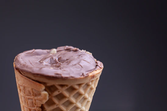 Close-up of a chocolate ice cream cone with a sleek CCTV camera wire subtly wrapped around it.