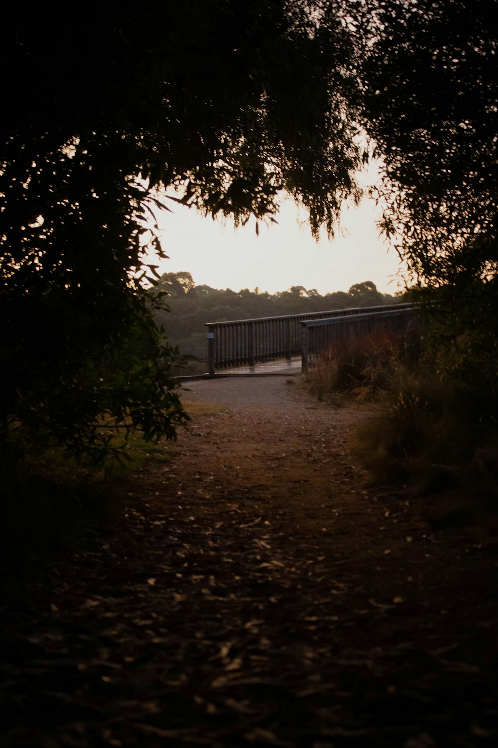 un chemin de terre avec un pont au loin