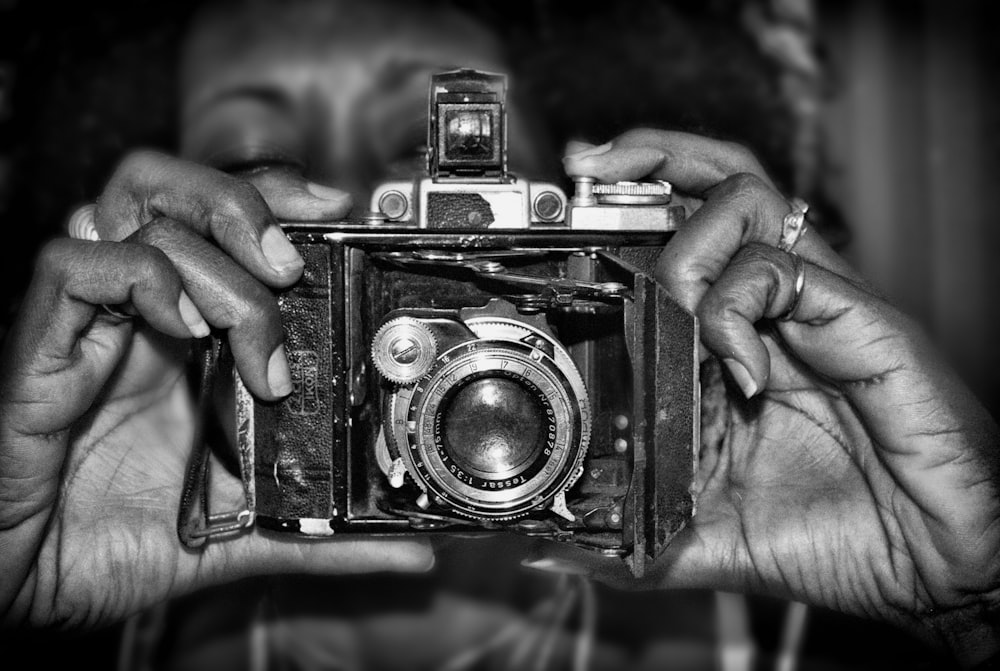 a black and white photo of a person holding a camera