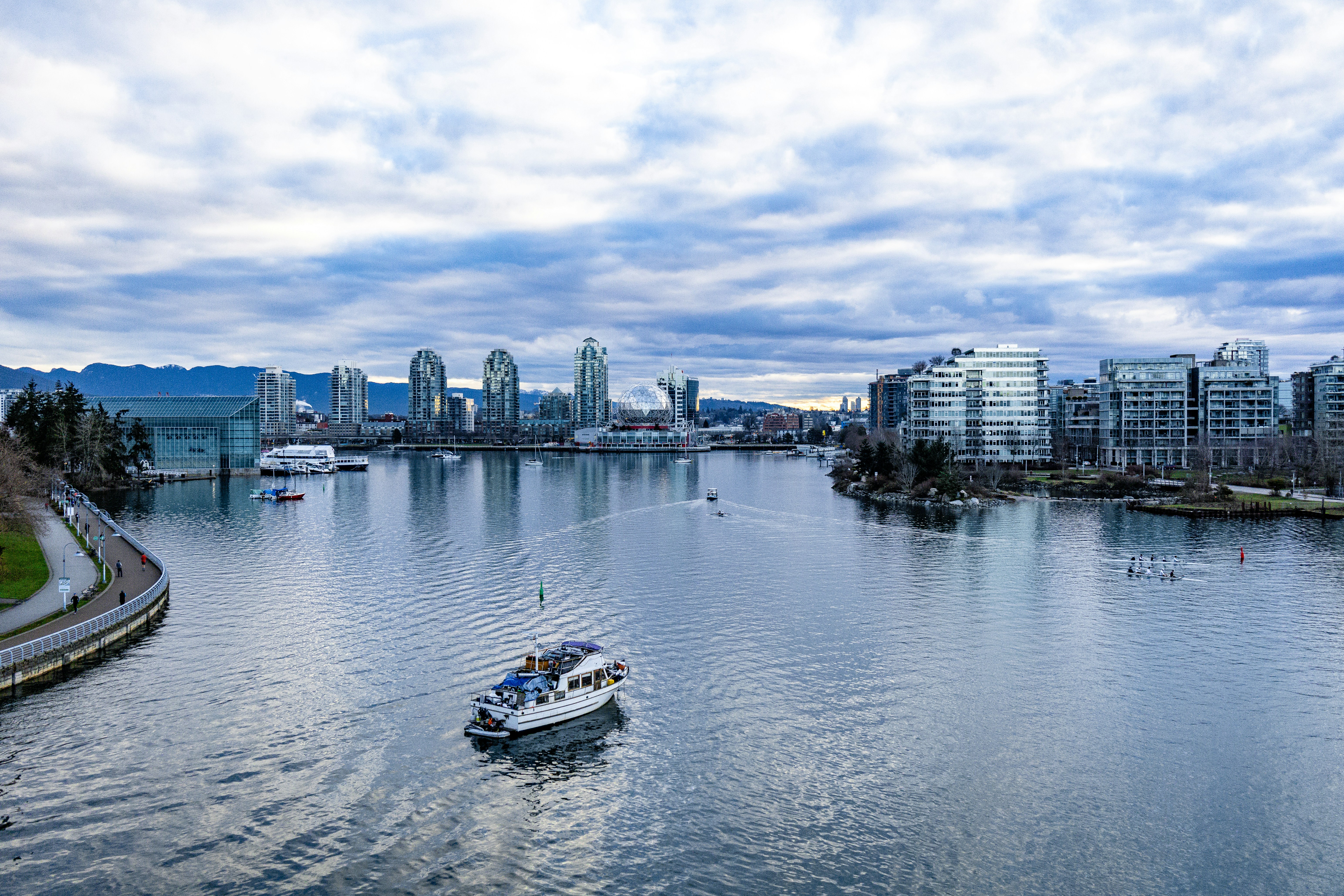 a boat traveling down a river next to a city, 