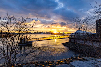 A vibrant sunset over NYC skyline viewed from a boat deck on the water.