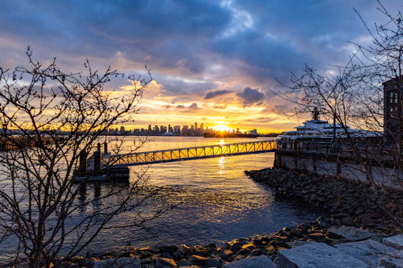 A vibrant sunset over NYC skyline viewed from a boat deck on the water.