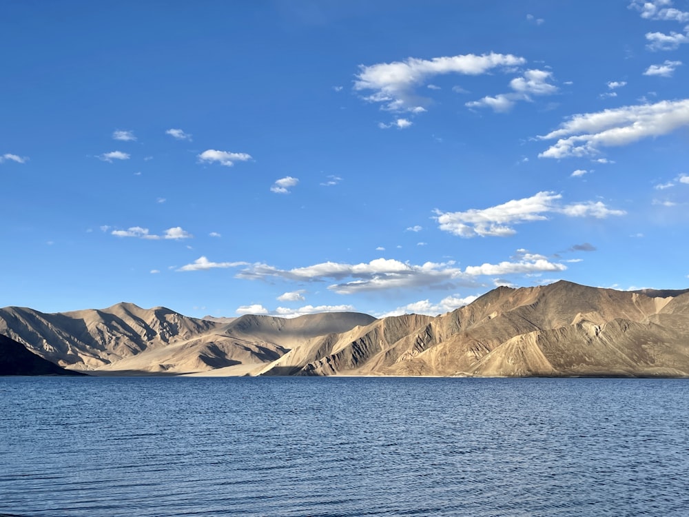 a body of water surrounded by mountains under a blue sky