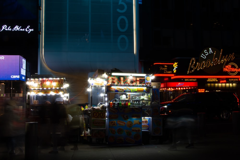 a street scene with a food cart and a neon sign