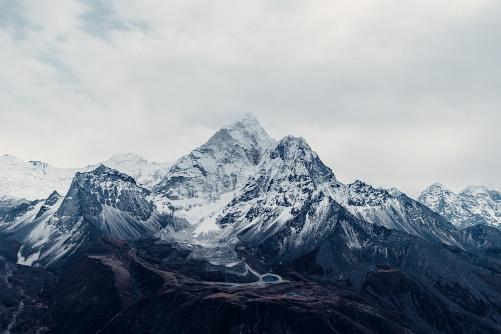 a snow covered mountain range under a cloudy sky