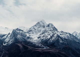 a snow covered mountain range under a cloudy sky