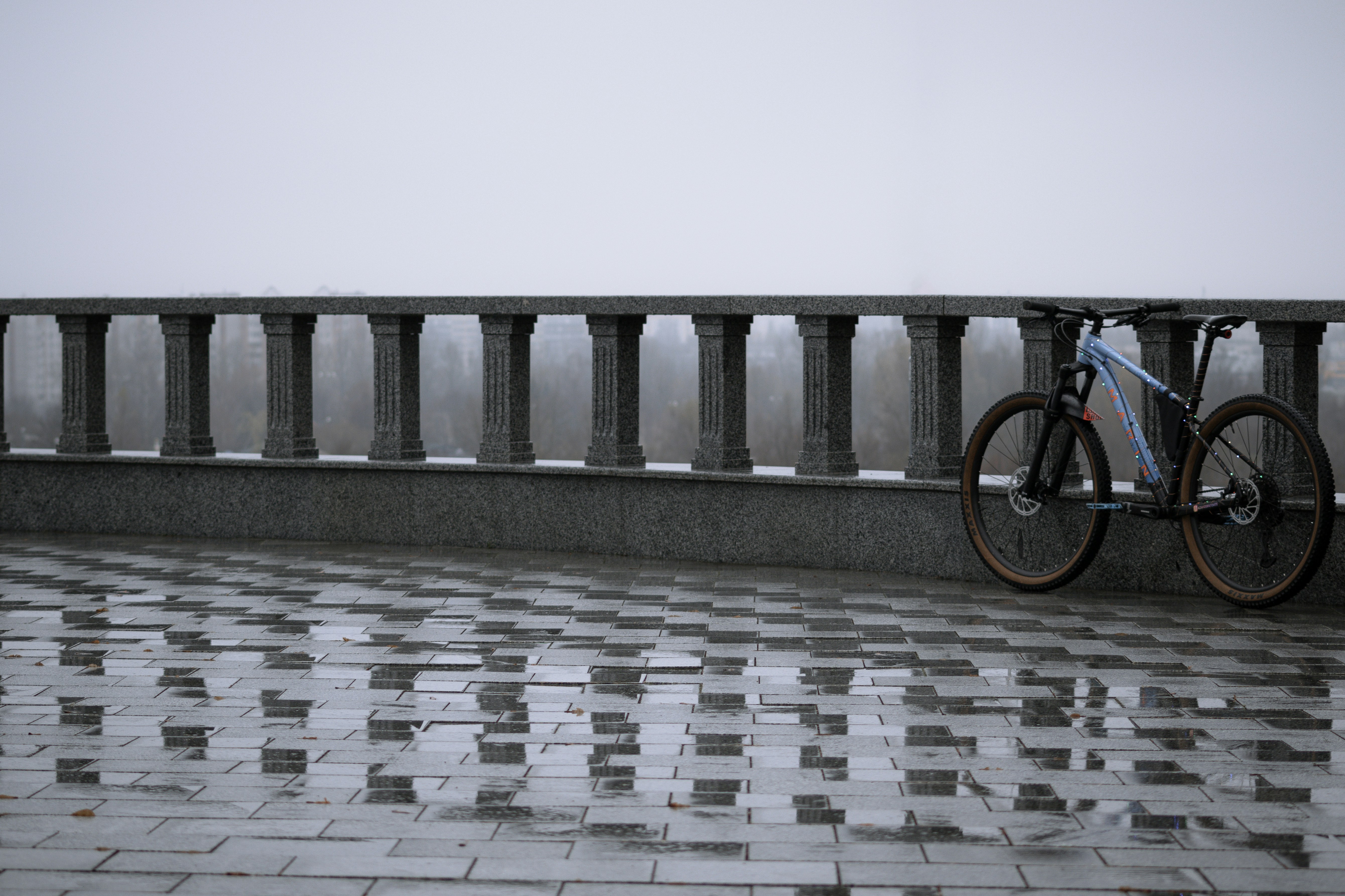 Una bicicleta estacionada en un puente bajo la lluvia