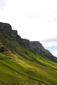 A stunning view of a mountain landscape with lush greenery and a clear blue sky.