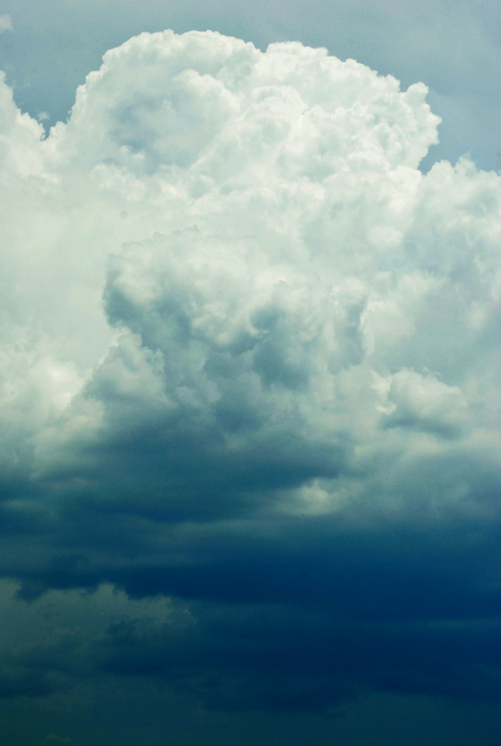 a plane flying through a cloudy blue sky