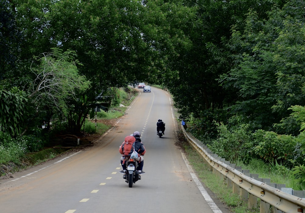 a couple of people riding motorcycles down a road