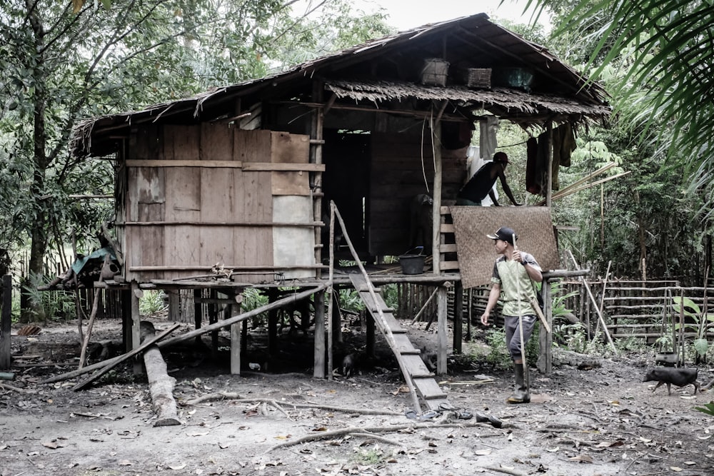 a man standing in front of a shack in the woods