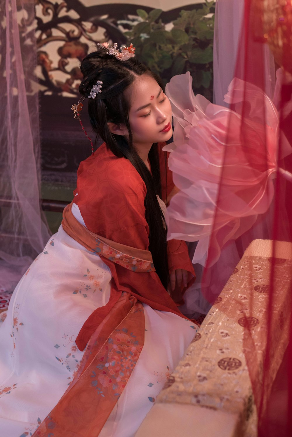 a woman in a red and white dress sitting on a bed