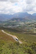 a car driving down a road with mountains in the background