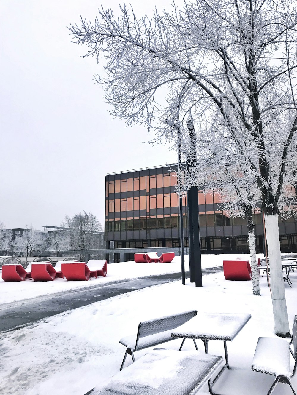 a snow covered park with benches and tables