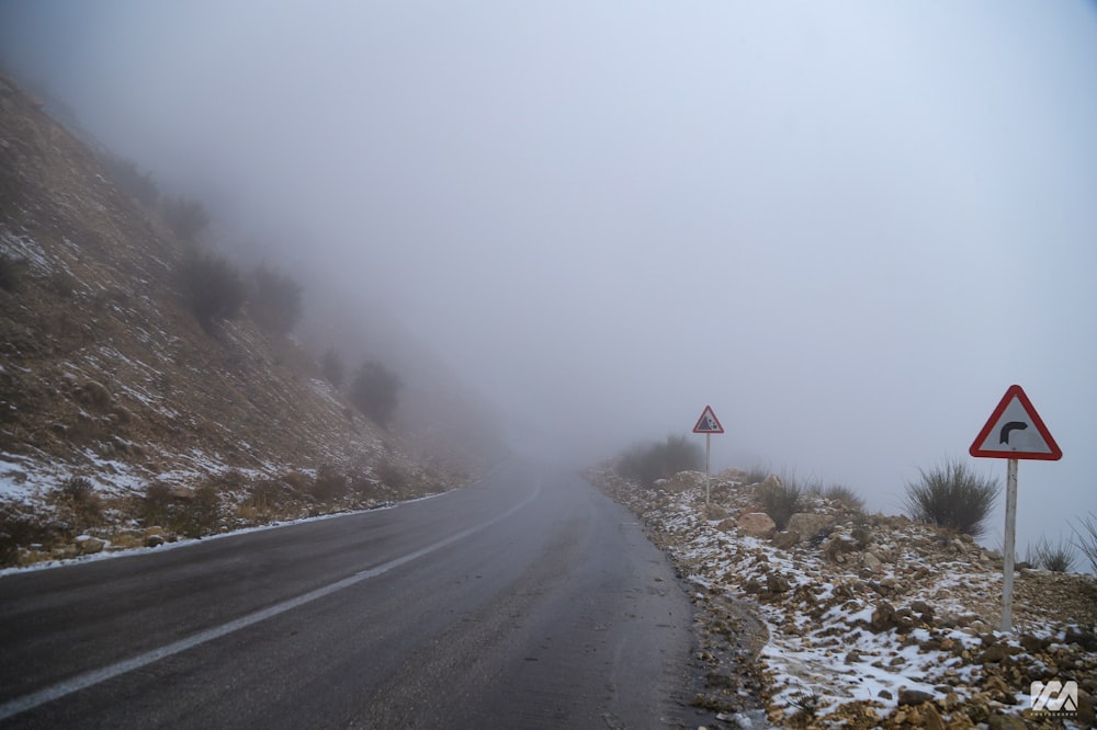 Una strada di montagna nebbiosa con un cartello rosso e bianco