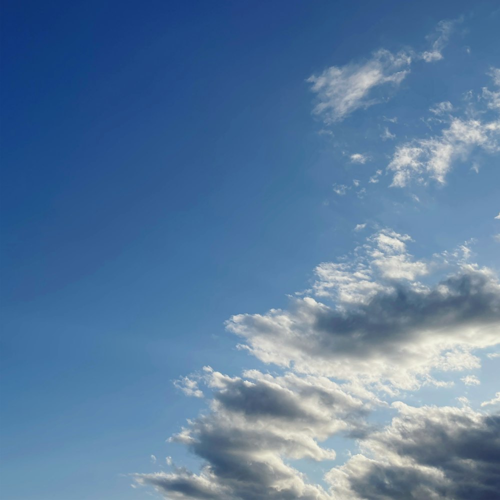 a plane flying through a cloudy blue sky