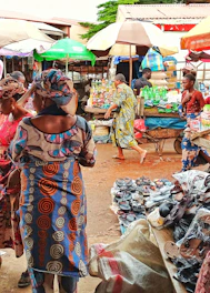 A group of refugee vendors happily selling goods at a bustling Soko Uganda market.