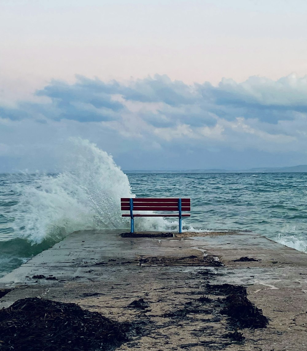 um banco sentado em cima de um cais ao lado do oceano