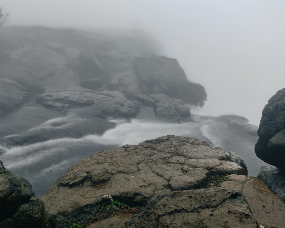 a river flowing between two large rocks on a foggy day