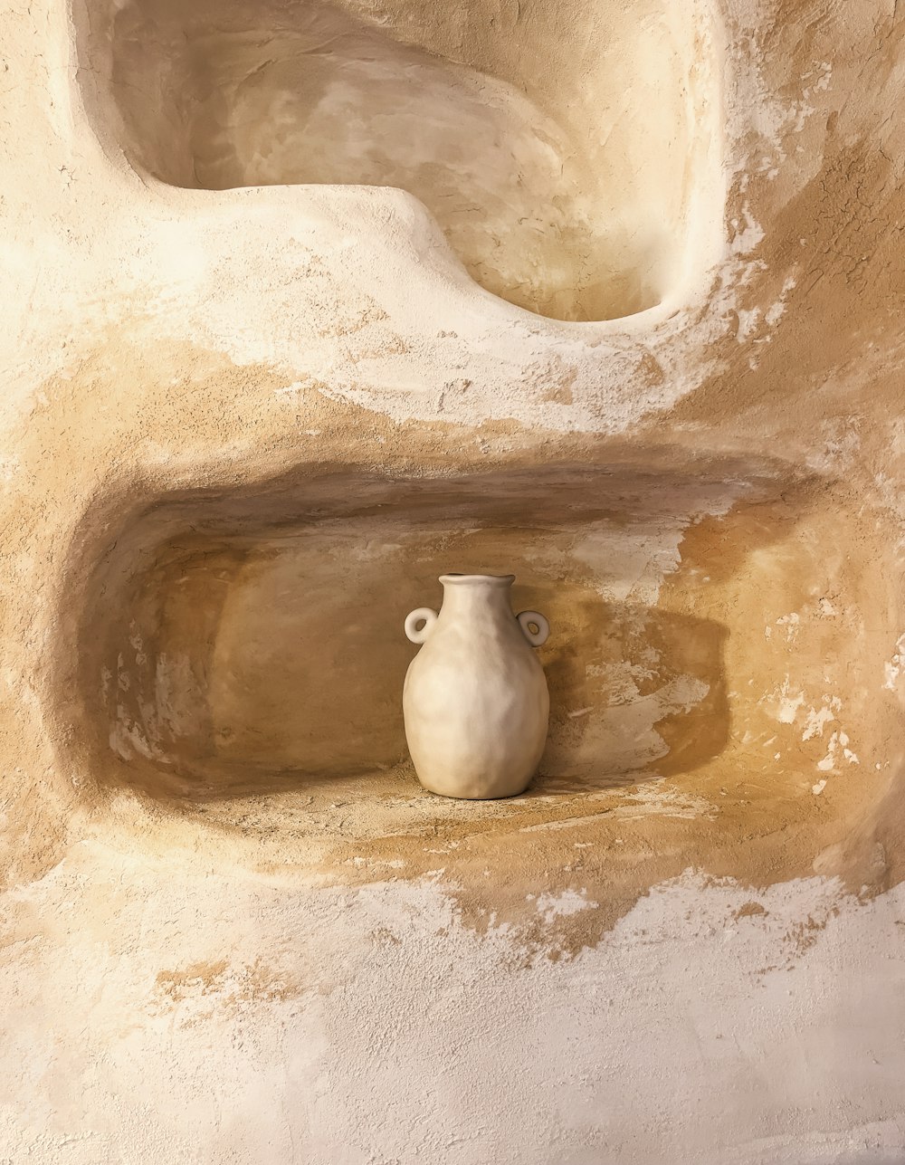 a white vase sitting on top of a cement wall