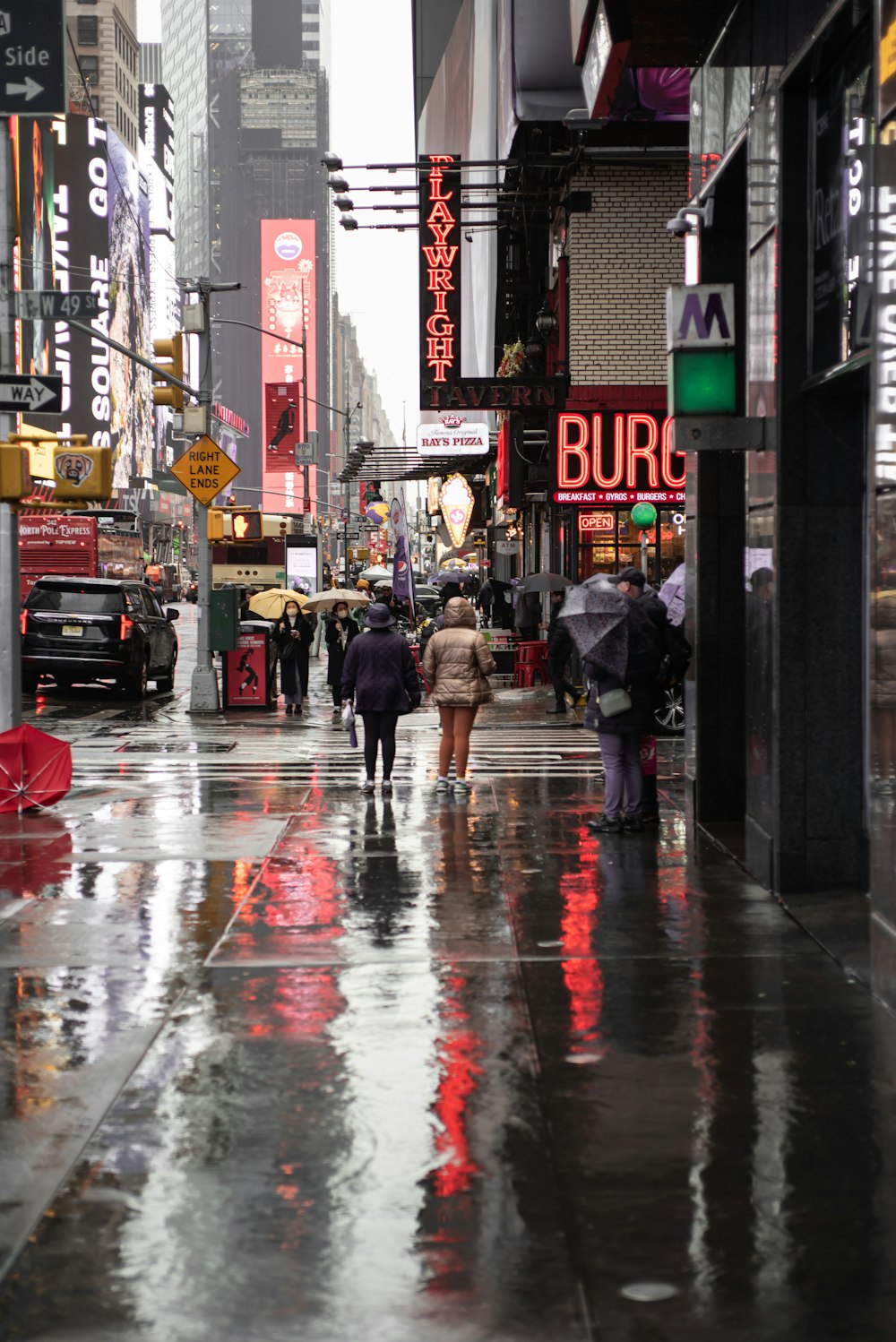 a wet city street with people walking down it