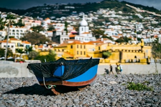 a blue and black boat sitting on top of a rocky beach