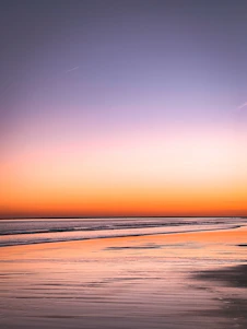 A serene Bali beach at sunrise with soft ocean blue and beige tones reflecting on calm waters.