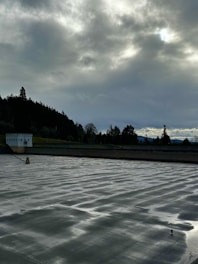 Technicians applying waterproof coating carefully on a large commercial floor site under cloudy skies.