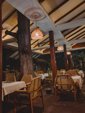 A cozy outdoor setup featuring wooden tables and white folding chairs with soft linen accents.