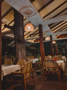 A cozy outdoor setup featuring wooden tables and white folding chairs with soft linen accents.