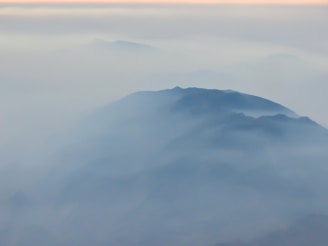 A peaceful Colombian mountain landscape at dawn with mist rolling over the hills.