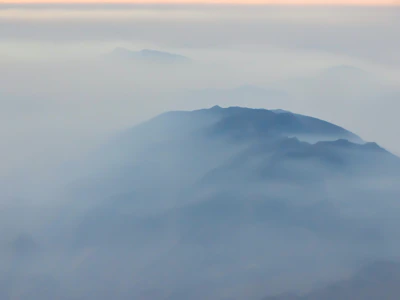 Wide shot of a peaceful mountain range shrouded in gentle morning mist.