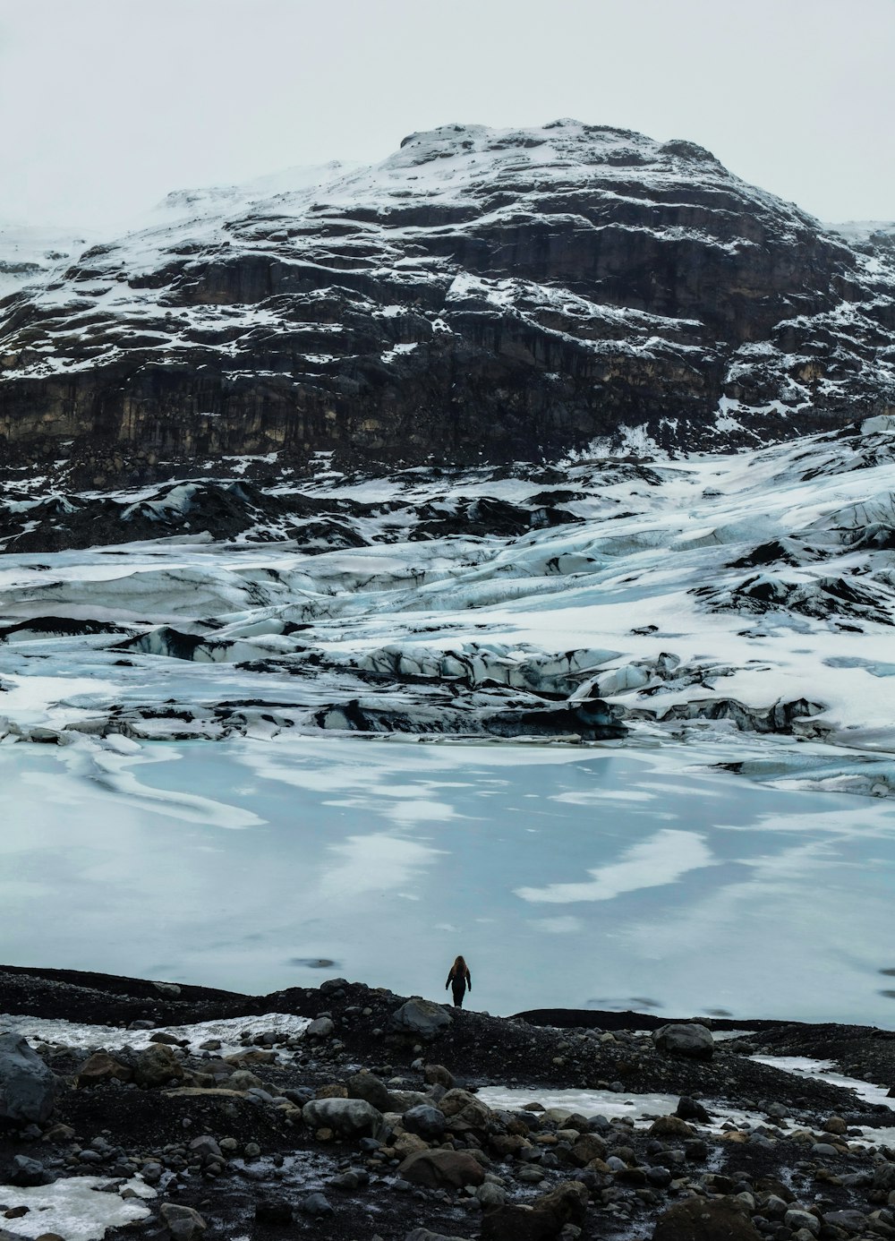 a person standing on a rocky area with a mountain in the background