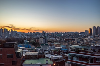 A cityscape showing a mix of residential and commercial buildings at sunset.