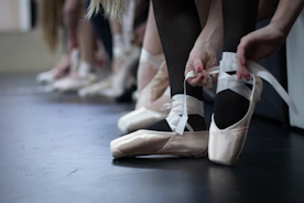 Close-up of hands tying ballet shoes, highlighting preparation and care.