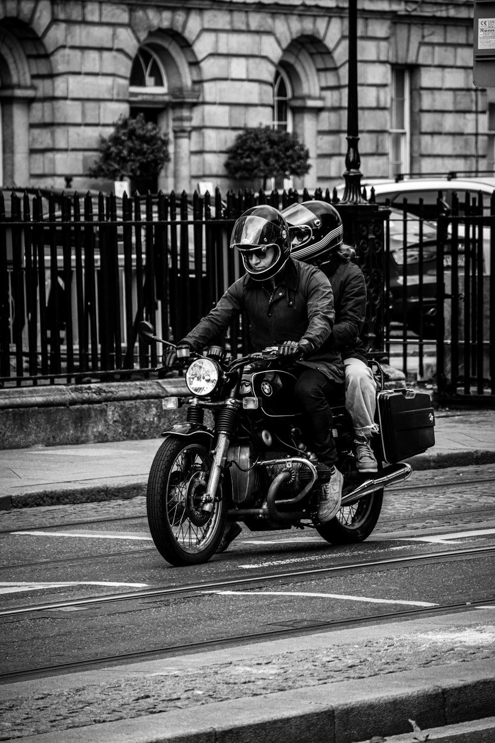 a man riding a motorcycle down a street next to a tall building