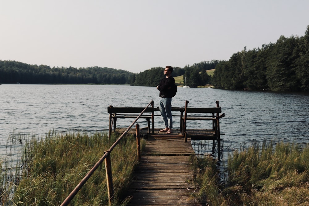 eine Person, die auf einem Dock neben einem Gewässer steht