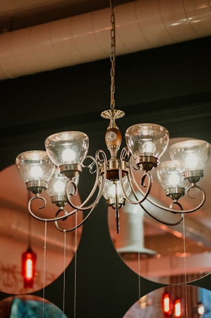 Technician carefully installing an elegant chandelier with royal blue walls in the background.