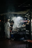 A bustling night scene with street food vendors serving local delicacies.