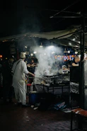 Two friends laughing while sharing street food at a bustling night market.