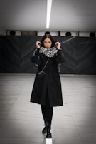 Side profile of a model in an awoke black jacket walking through a minimalist gallery space.